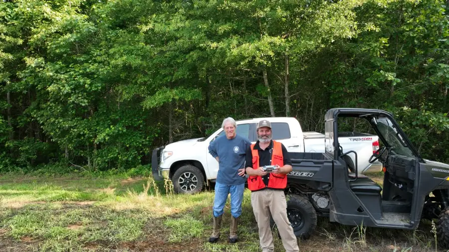 Eric Entrekin with a landowner beside a pickup in the woods